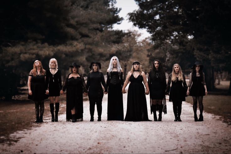 a group of women dressed in black standing next to each other on a dirt road