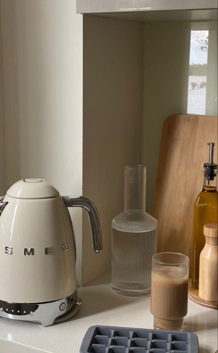 a coffee maker sitting on top of a kitchen counter next to a glass and bottle