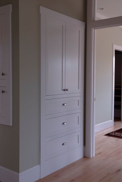 an empty room with wooden floors and white cupboards on the wall next to a door