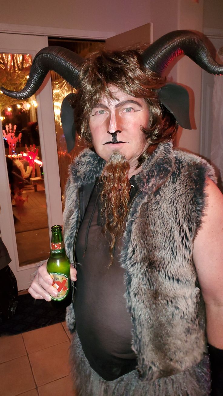 a man with horns and beard holding a beer in his hand while wearing a costume