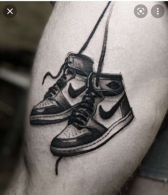 a black and white photo of a pair of sneakers on the thigh with a rope