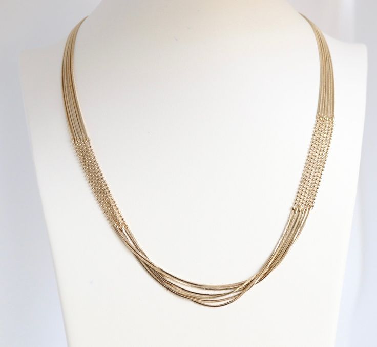 The elegant gold layered necklace boasts a sophisticated design with beaded sections on both sides, adding a touch of refinement and charm. Its multi-layered structure creates a statement piece that gracefully enhances any neckline, making it a versatile and eye-catching addition to your jewelry collection. Elegant Gold-tone Snake Chain Necklace, Elegant Necklace With Delicate Metal Chain, Elegant Metal Necklace With Delicate Chain, Elegant Gold Layered Necklace With Adjustable Chain, Party Gold-plated Double Chain Necklace, Elegant Multi-strand Gold Plated Necklace, Yellow Gold Multi-strand Necklaces For Formal Occasions, Elegant Gold Metal Snake Chain Necklace, Elegant Silver Layered Gold-plated Necklace