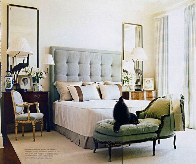 a cat sitting on top of a bed in a bedroom next to a dresser and chair