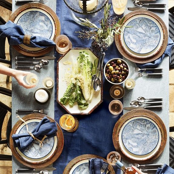 an overhead view of a table setting with plates, silverware and blue napkins