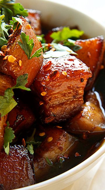 a white bowl filled with cooked meat and garnished with cilantro leaves