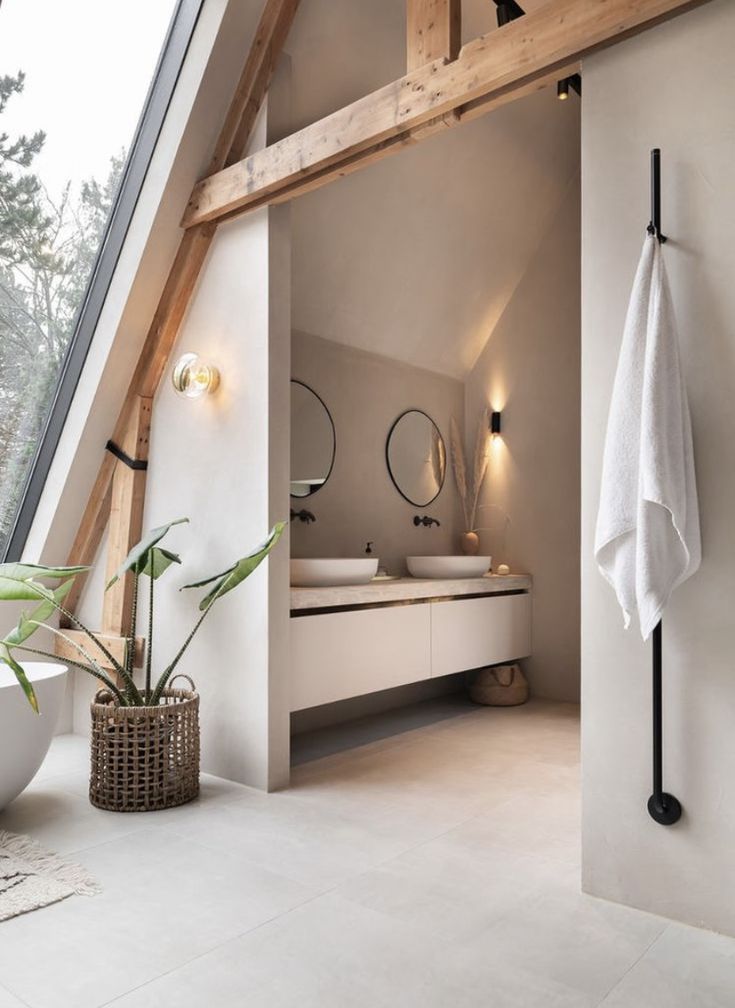 a white bathroom with two sinks and a large window in the corner, along with a potted plant