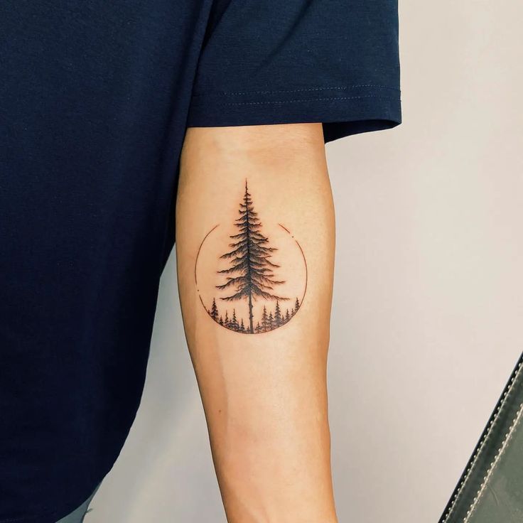 a man's arm with a pine tree tattoo on the left side of his arm