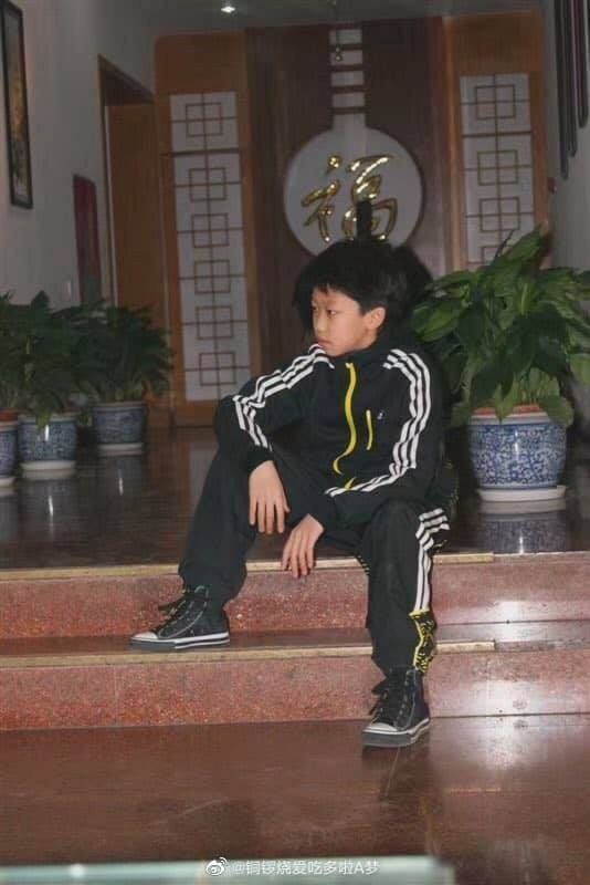 a young boy sitting on the steps in front of a plant