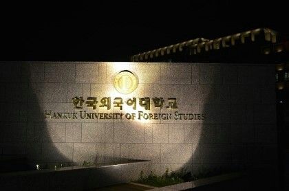 an illuminated sign for the university of foreign studies in front of a building at night