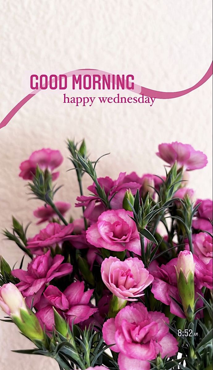 a vase filled with pink flowers sitting on top of a table next to a white wall