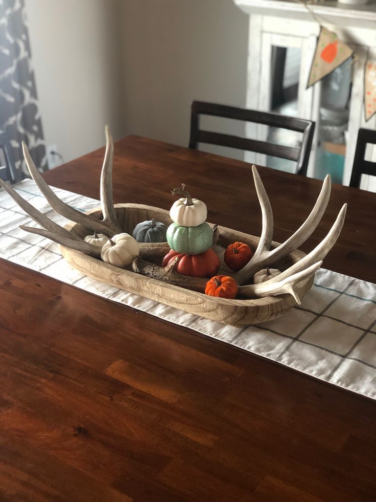 an antler with pumpkins and gourds in it sitting on a table