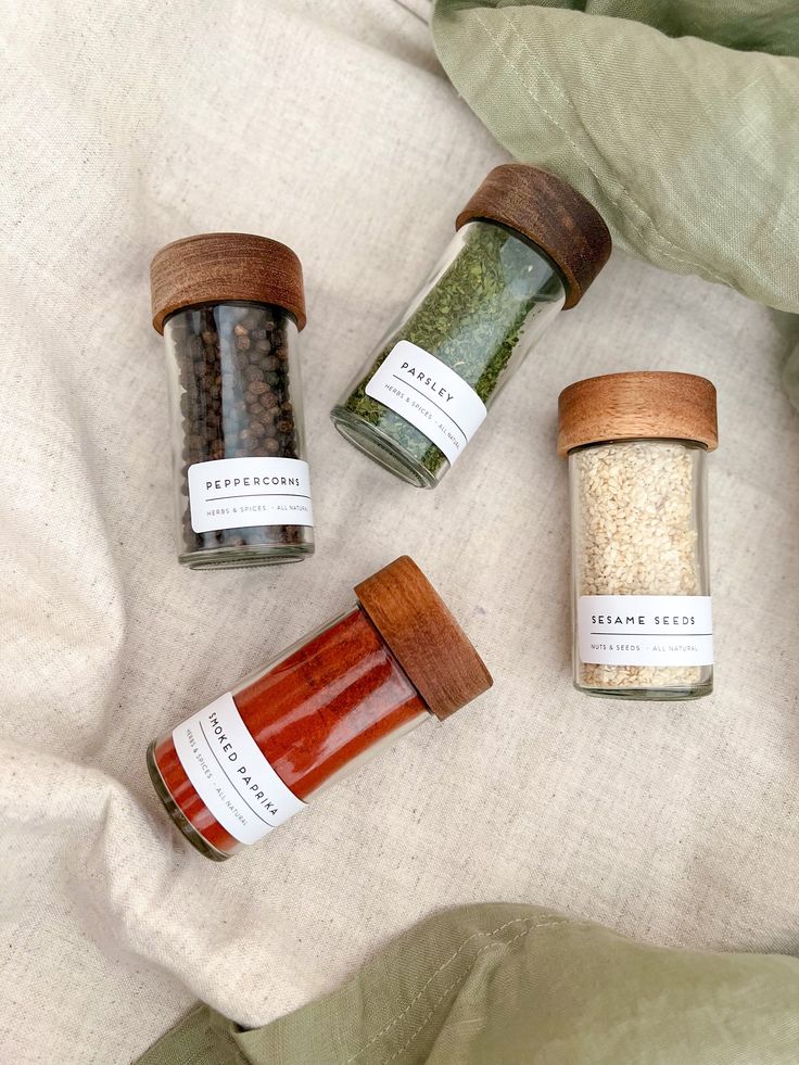 four spice jars sitting on top of a bed next to each other with different types of spices in them