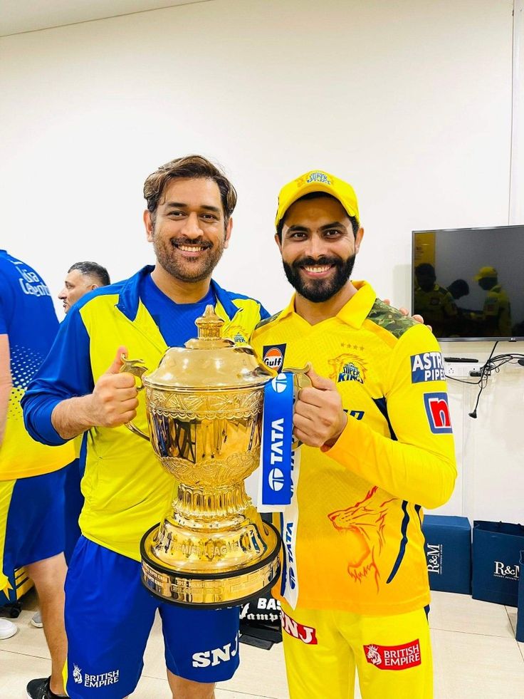 two men in yellow and blue uniforms hold up a trophy while standing next to each other