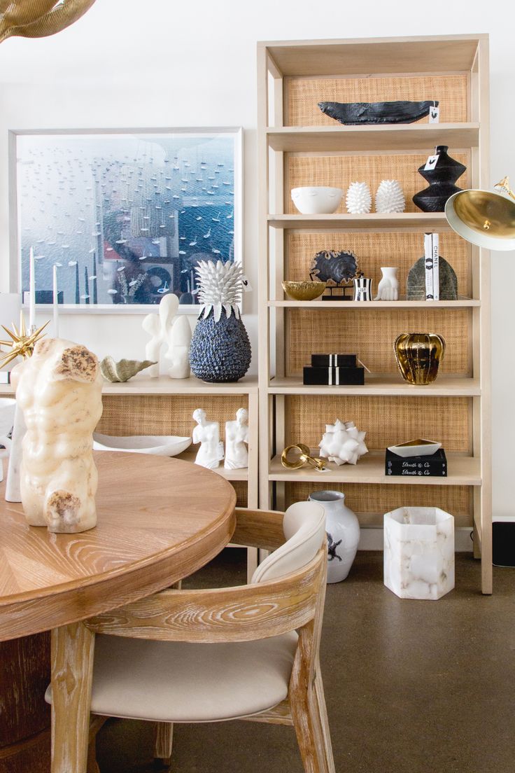 a wooden table sitting in front of a bookshelf filled with vases and other items