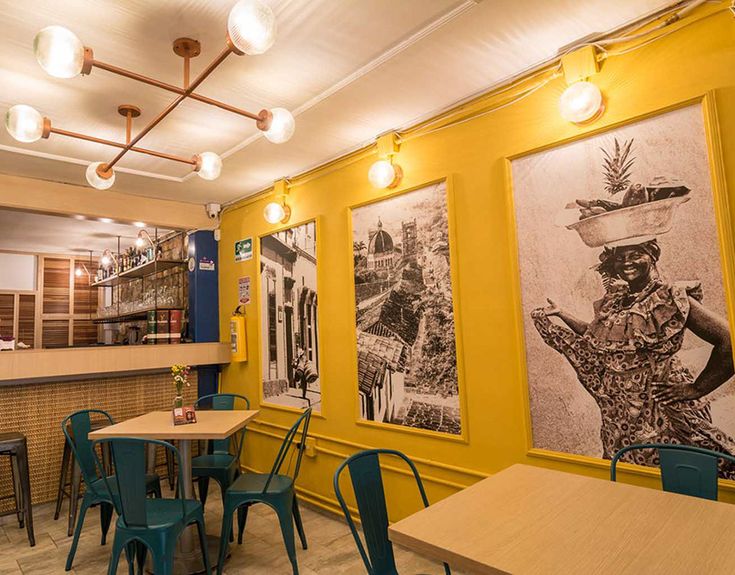 an empty restaurant with tables and chairs in front of large pictures on the wall behind them