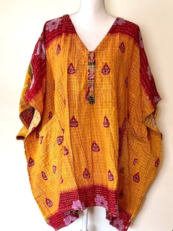 Mini Muu Kantha Embroidered Tunic is made from 100% cotton lux sari. Features a V-neck with 3 functional buttons and two exterior slouchy pockets in front. The depth of color, blend of patterns, rich luxe fabric will quickly become one of your favorite pieces.This is a new and unique style. Each print tunic is one of a kind and a true designer piece. One size fits most.A versatile tunic with functional buttons, allowing you to style as a blouse, mini dress and or cover-up. Wear it as a kantha sh Traditional Bandhani Print Kaftan For Festivals, Summer Bandhani Print Kaftan, Traditional Yellow V-neck Kurta, Yellow V-neck Traditional Kurta, Yellow Free Size Traditional Kaftan, Traditional Yellow Free Size Kaftan, Yellow Bohemian Tops For Festivals, Traditional Yellow Free-size Kaftan, Yellow Bohemian Kurta For Beach