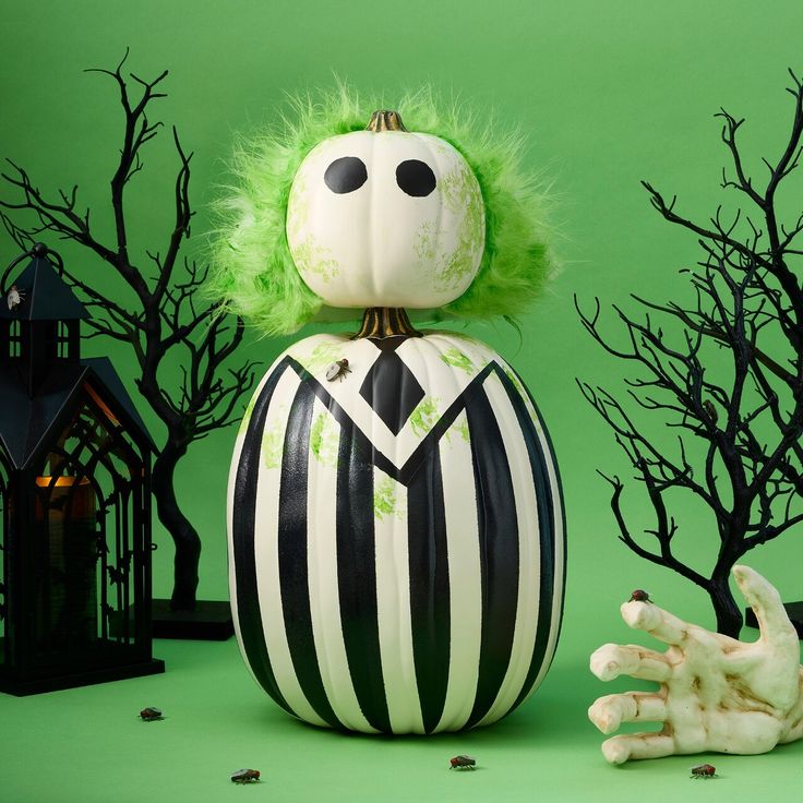 a green and black striped pumpkin sitting on top of a table next to a creepy hand