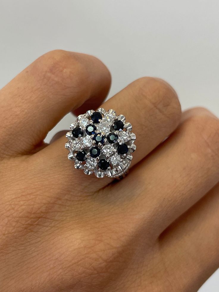 a woman's hand wearing a ring with black and white stones