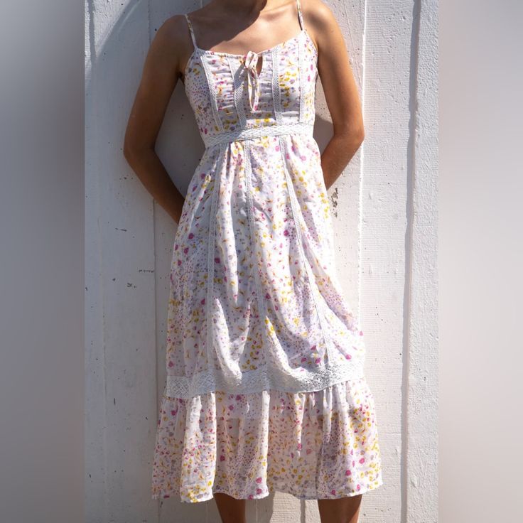 Beautiful Maxi Dress Comes With Adjustable Spaghetti Straps And A Sheer Lining. Has Pink, Yellow And Lilac Floral Patterns. It Is Not See Through And Has An Open Tie Front Chest. Has A Smocked Back And Crotchet Detailing. Material Is Very Lightweight, Gives An Effortless And Very Comfortable Feel. So Pretty! Perfect For Springtime! It Does Not Reach The Floor, More Of A Midaxi Fit (Between A Midi And Maxi). New With Tags. Find Me On Curtsy @ Lola M. New Users Use Code Alondrac95 For $$ Off Your Spring Sundress With Ditsy Floral Print And Spaghetti Straps, White Feminine Sundress With Spaghetti Straps, White Fitted Sundress With Tie Straps, Fitted White Sundress With Tie Straps, White Spring Dress With Tie Straps, Feminine Spaghetti Strap Dresses For Daytime, Spring White Dresses With Tie Straps, White Feminine Sundress With Tie Straps, White Sundress With Tie Straps