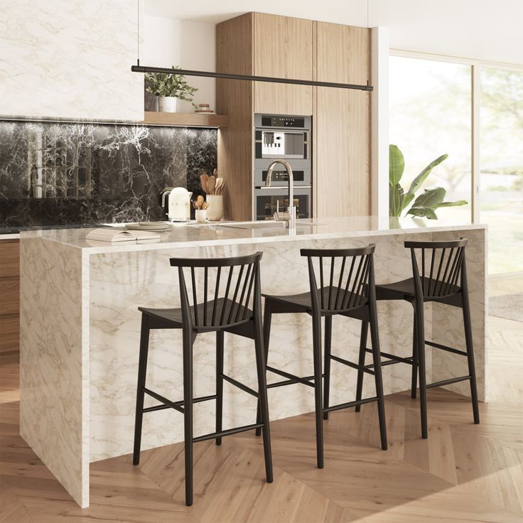 three black chairs sit at the bar in this modern kitchen with marble countertops and cabinets