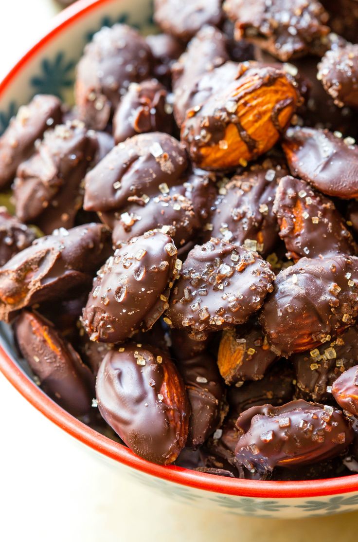 a bowl filled with chocolate covered almonds and sprinkled with sea salt on top