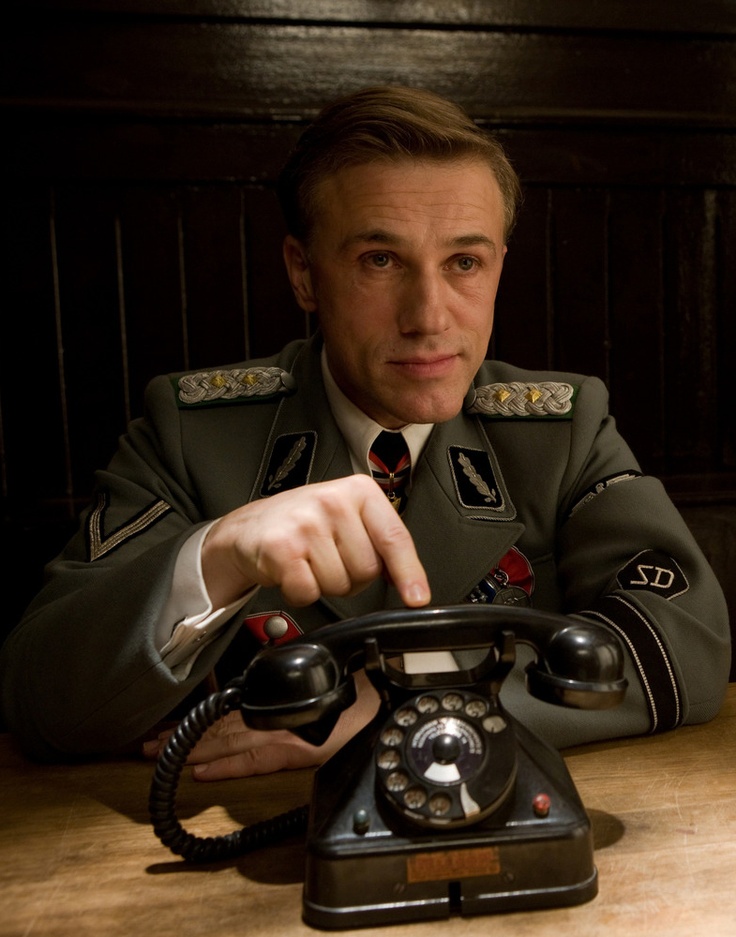 a man in uniform sitting at a table with an old phone