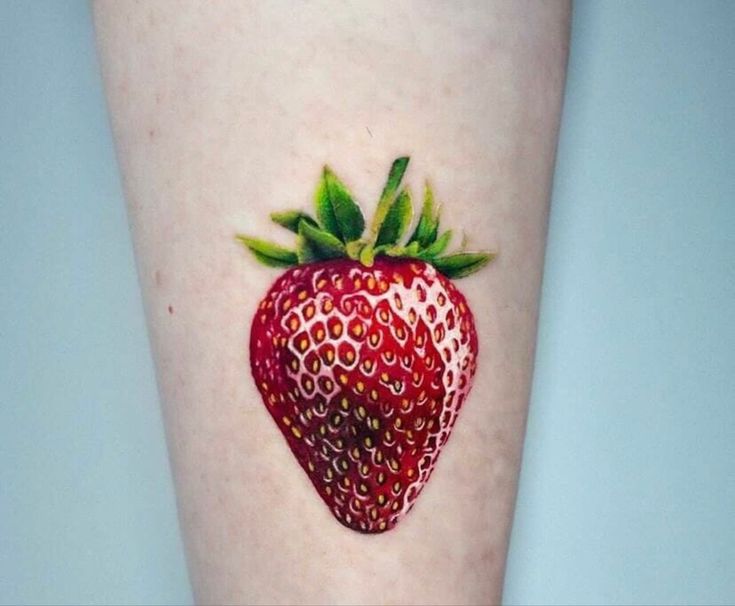 a small strawberry tattoo on the leg