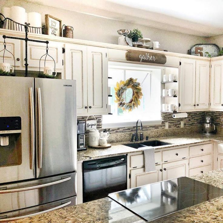 a kitchen with granite counter tops and stainless steel appliances, wreath on the wall above the sink