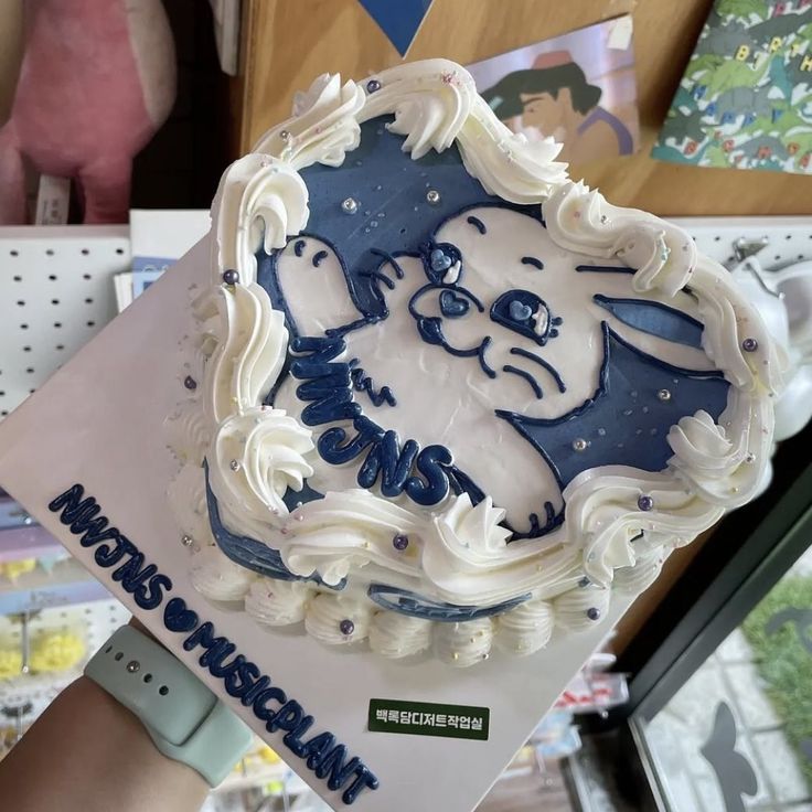 a person holding up a cake with frosting on it