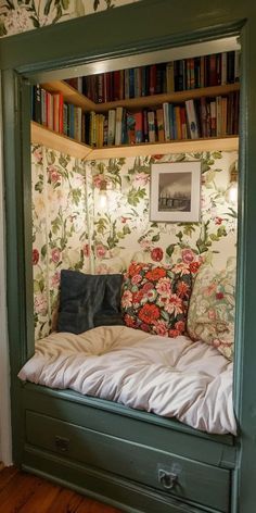 a bed in a room with bookshelves and floral wallpaper on the walls