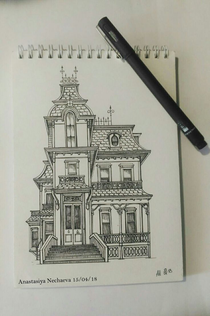 a drawing of a house on top of a notebook with a pen next to it