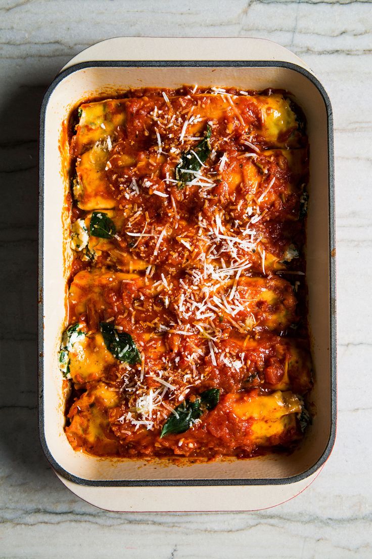 a casserole dish with cheese and spinach in it on a marble surface