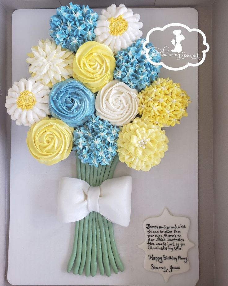 a bouquet of flowers made out of fondant in a box with a white bow