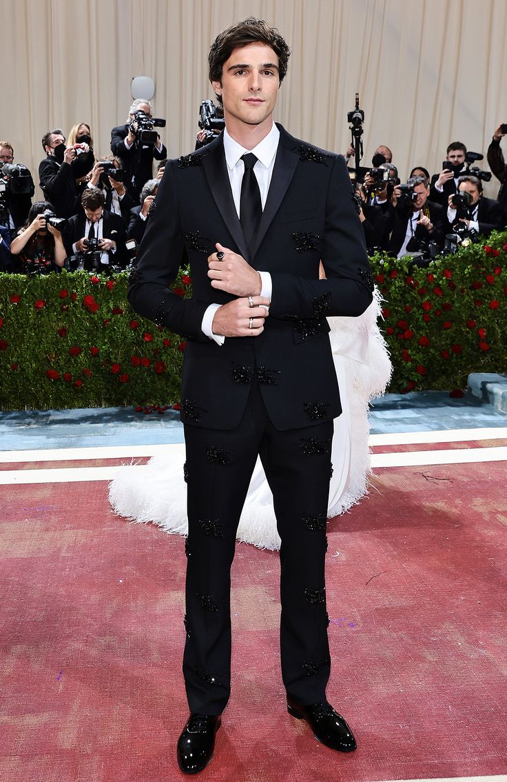 a man in a tuxedo standing on a red carpet