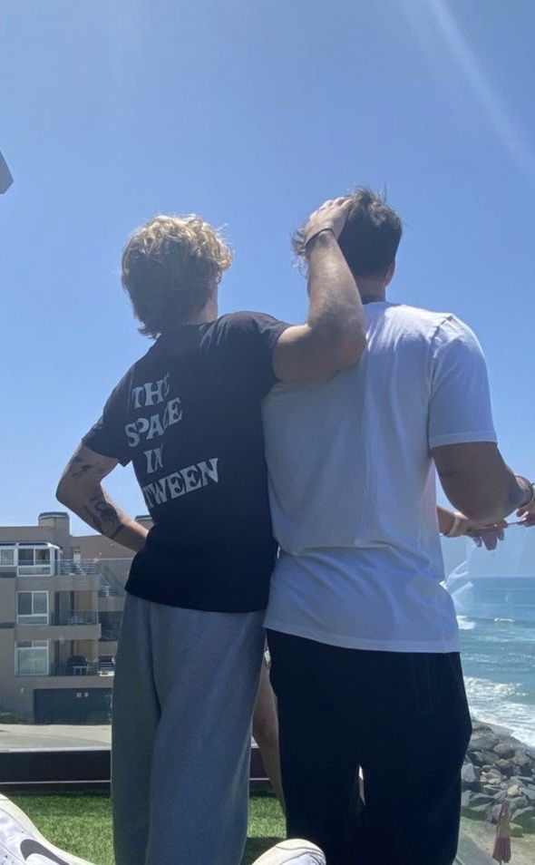 two men standing next to each other near the ocean