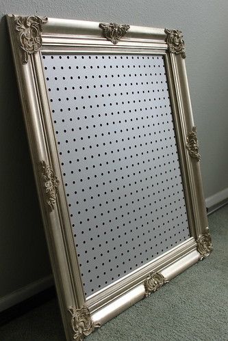 a large silver framed mirror sitting on the floor in front of a wall with polka dots