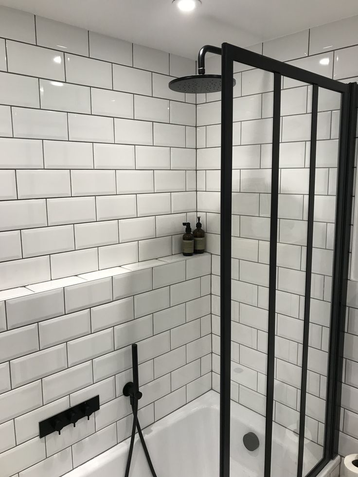 a bathroom with white tile and black fixtures