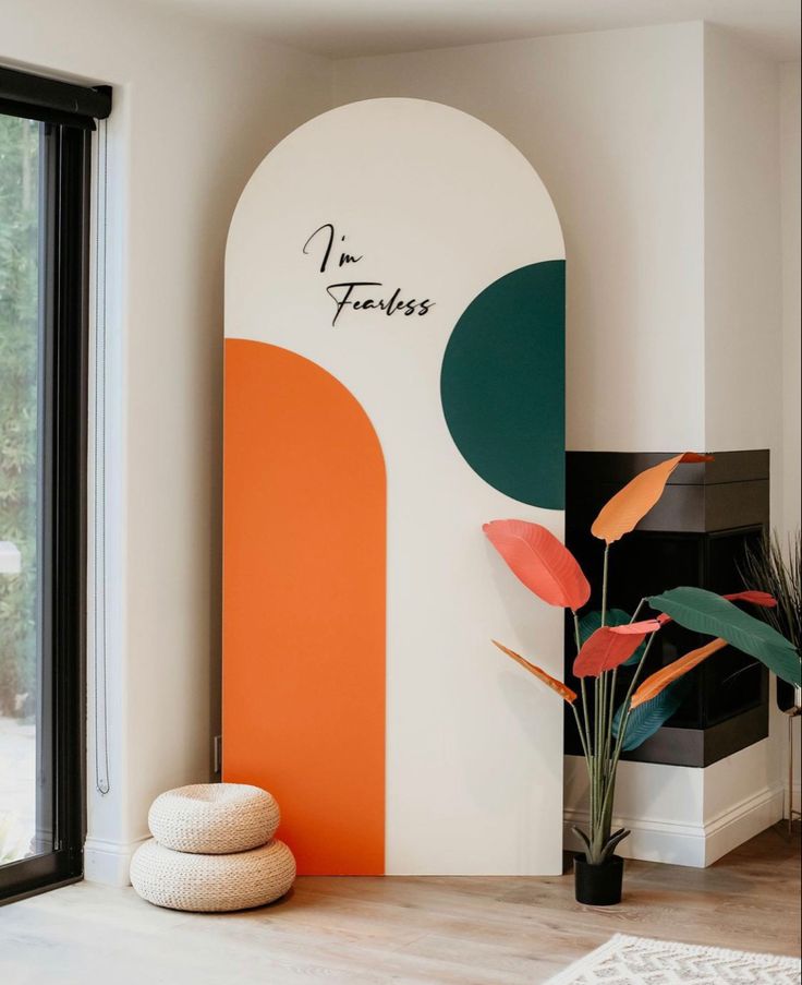 a living room with an orange and white wall next to a plant on the floor