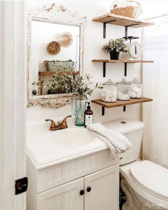 a white toilet sitting next to a bathroom sink under a mirror with shelves above it