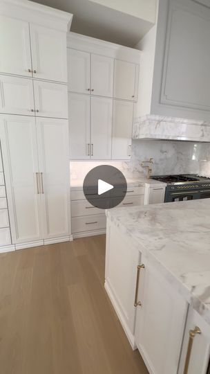 a kitchen with white cabinets and marble counter tops