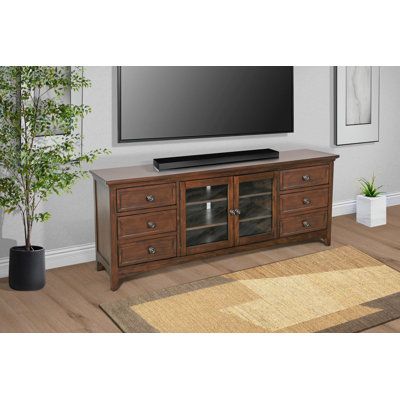 a flat screen tv sitting on top of a wooden entertainment center next to a potted plant