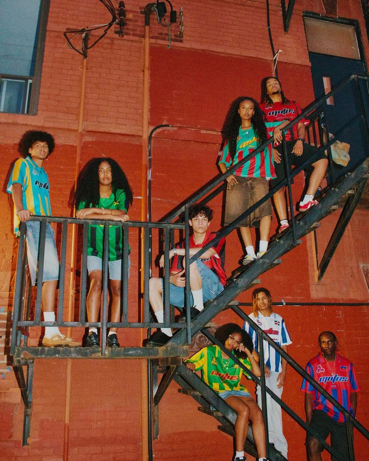 the group of young people are standing on the stairs outside an apartment building with their hands in their pockets