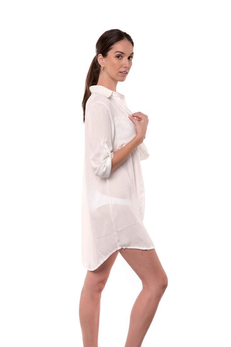 The Lydia is a button-up cover-up that can double as a shirt for a casual look. The off-white fabric has a light texture, and it is breathable and comfortable. The long sleeves can be folded and secured with a button on the side. One size. one size shoulder to bottom length: 35" (89cm) sleeves length: 21" (54cm) 100% Rayon (Viscose) Chic White Blouse With Roll-up Sleeves, Summer Long Sleeve Blouse With Roll-up Sleeves, Summer Blouse With Roll-up Sleeves, Chic Long Sleeve Beach Shirt, Chic Long Sleeve Shirt For Beach, White Button Closure Shirt Dress For Beach, White Summer Shirt Dress With 3/4 Sleeves, White 3/4 Sleeve Shirt Dress For Summer, Beach Shirt With Long Roll-up Sleeves