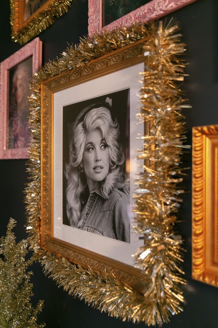 there is a gold tinsel frame hanging on the wall next to some framed pictures