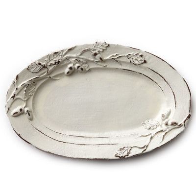 an oval silver platter with flowers and leaves on the rim, set against a white background