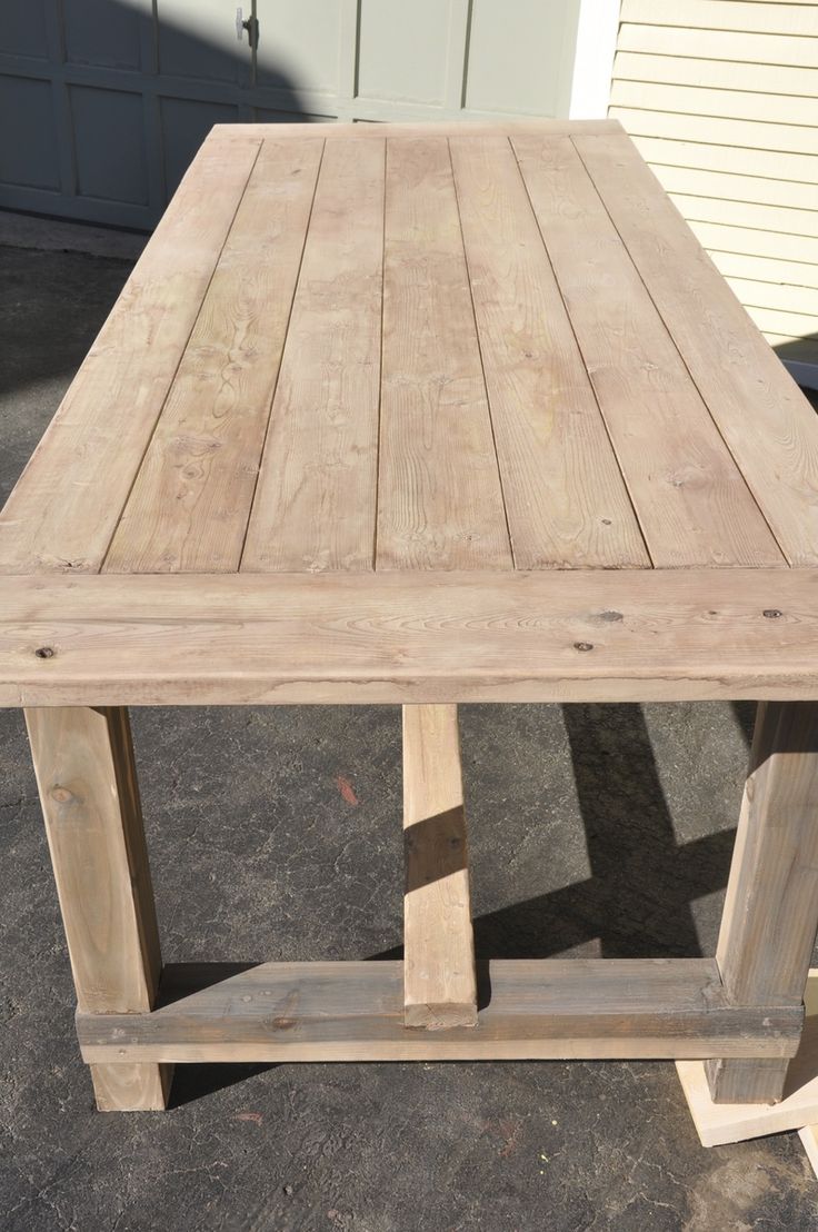 a wooden table sitting on top of a cement ground next to a garage door and building