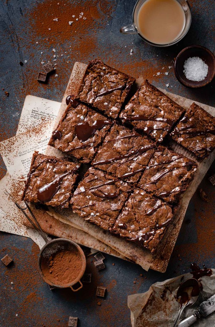 chocolate brownies on a cutting board next to two cups of coffee