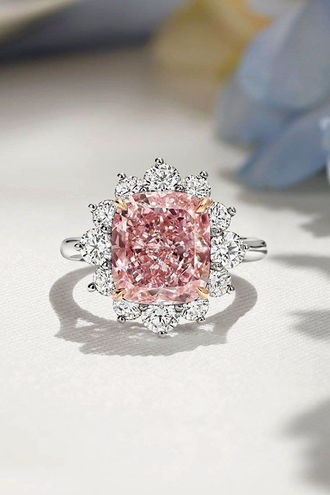 a pink diamond surrounded by white diamonds on top of a table with flowers in the background