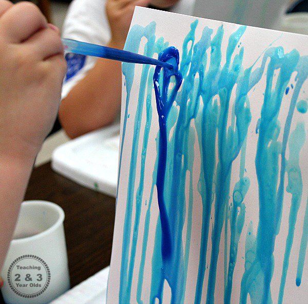 a person is painting with blue paint on paper