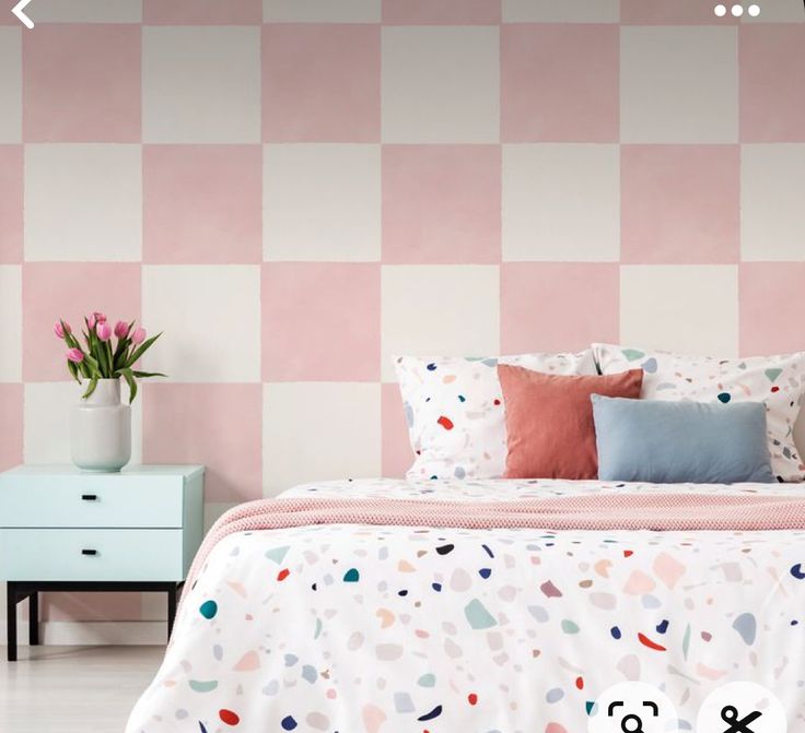 a bedroom with pink and white checkered wallpaper, bedding and nightstands